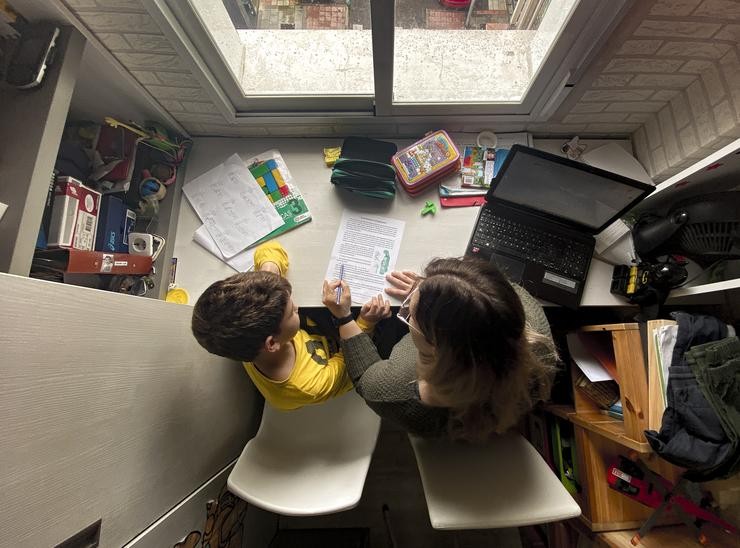 Un neno estuda e fai os deberes en casa coa axuda da súa nai 