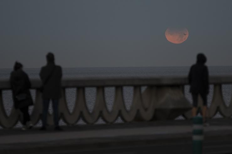 Tres persoas observan a eclipse lunar parcial desde A Coruña, a 19 de novembro de 2021, na Coruña, Galicia, (España).. M. Dylan - Europa Press 