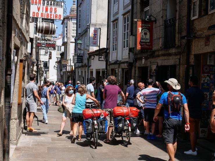 Varios peregrinos camiñan coa súa bicicleta pola Rúa do Franco de Santiago 