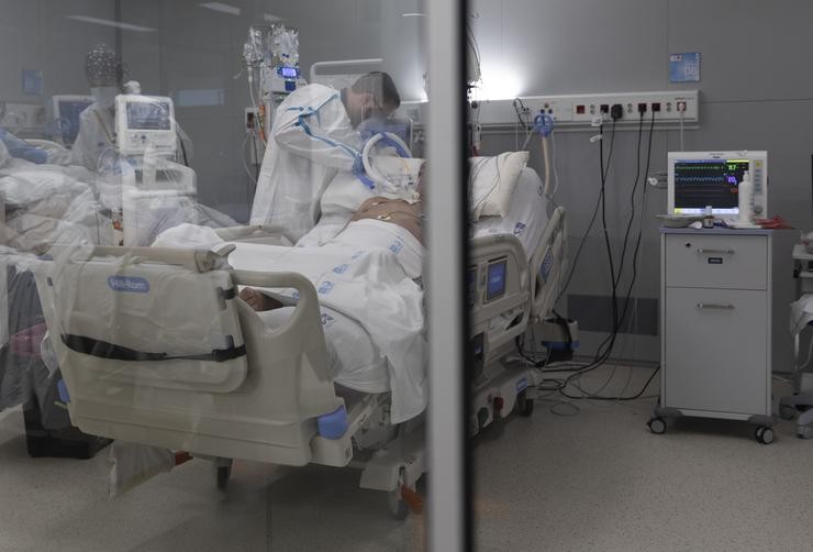 Un sanitario atende un paciente con covid-19 ingresado na UCI do Hospital Isabel Zendal de Madrid 