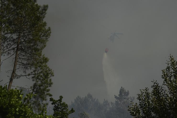 Un helicóptero traballa na extinción dun incendio forestal 