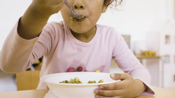 Nena comendo no comedor escolar 