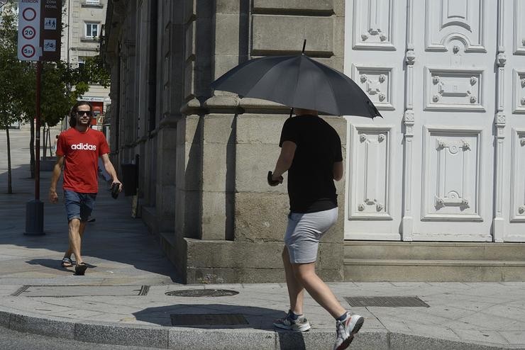 Dúas persoas camiñan por unha vía en plena onda de calor, a 12 de xullo de 2022, en Ourense 