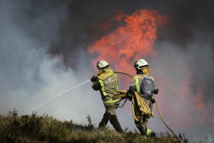 Efectivos da Xunta con base en Becerreá traballan para extinguir as chamas nun incendio forestal.