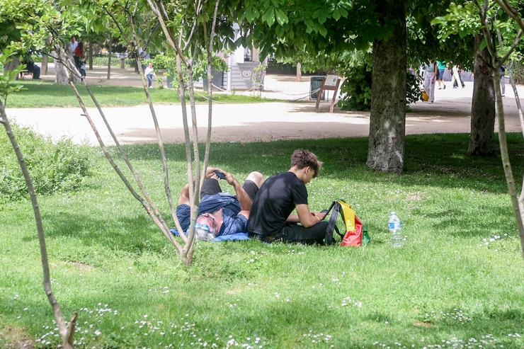 Varias persoas descansan nun parque nun día de sol, calor e altas temperaturas 