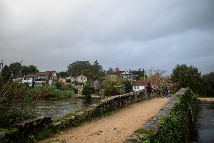 Varias persoas cruzan unha ponte observando a crecida do río Tea, a 4 de novembro de 2023, en Ponteareas, Pontevedra 