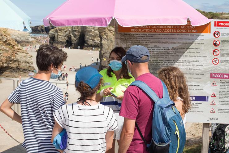 Turistas mostran os seus pases para acceder á praia das Catedrais.