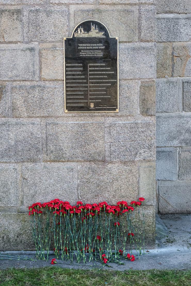 Caraveis vermellos baixo a placa cos nomes dos 21 falecidos na Vila de Pitanxo. 