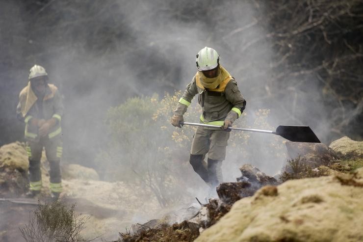 Dous brigadistas forestais traballan para extinguir as chamas nun incendio forestal, a 30 de marzo de 2023, en Baleira 