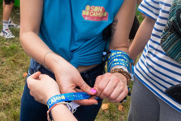 Arquivo - Unha moza pon unha pulseira na zona de acampada no festival Oson de Camiño, no Monte do Gozo, a 15 de xuño de 2022, en Santiago de Compostela. César Arxina - Europa Press - Arquivo 