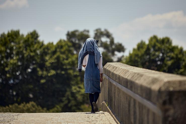 Unha persoa protéxese do sol nunha ponte da cidade de Ourense 