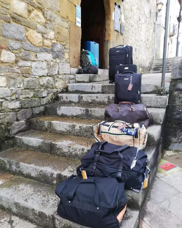 Maletas e mochilas ás portas dun albergue 
