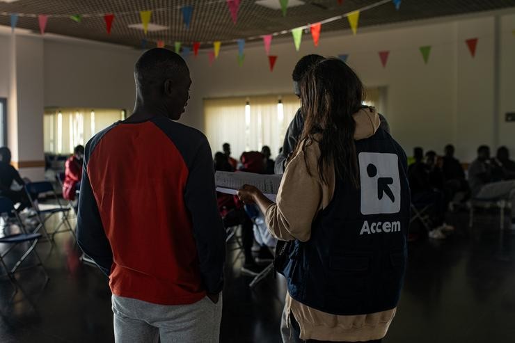 Varios migrantes procedentes de Canarias cunha voluntaria de Accem, na Casa de Cultura de Dorrón, a 17 de novembro de 2023, en Sanxenxo 