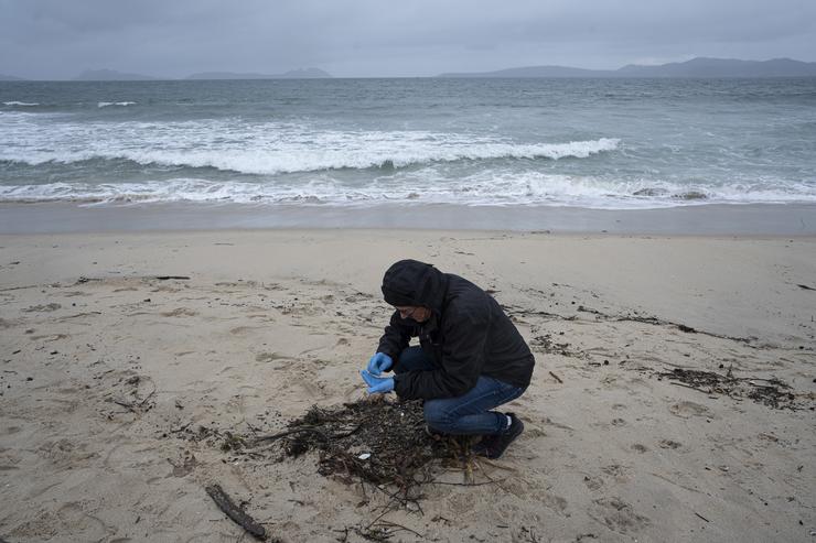 Un voluntario recolle pélets na praia de Samil 