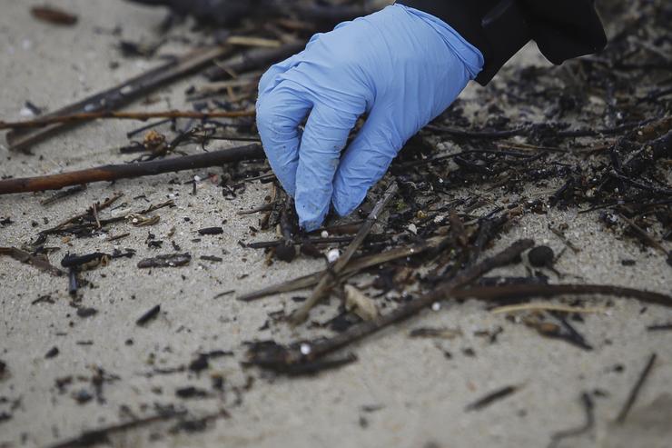 Un voluntario recolle pellets na praia de Samil, a 10 de xaneiro de 2024, en Vigo 