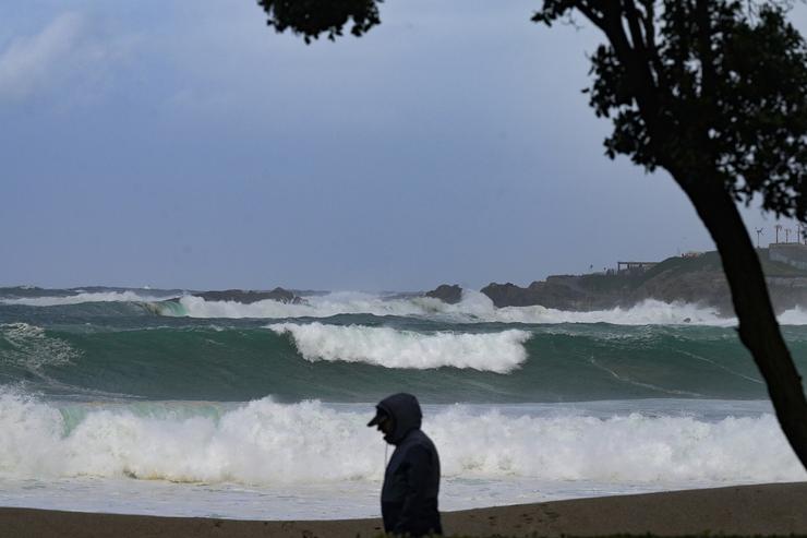Unha persoa camiña diante das ondas durante a fronte meteorolóxica, a 23 de febreiro de 2024, na Coruña, Galicia (España).. M. Dylan - Europa Press 