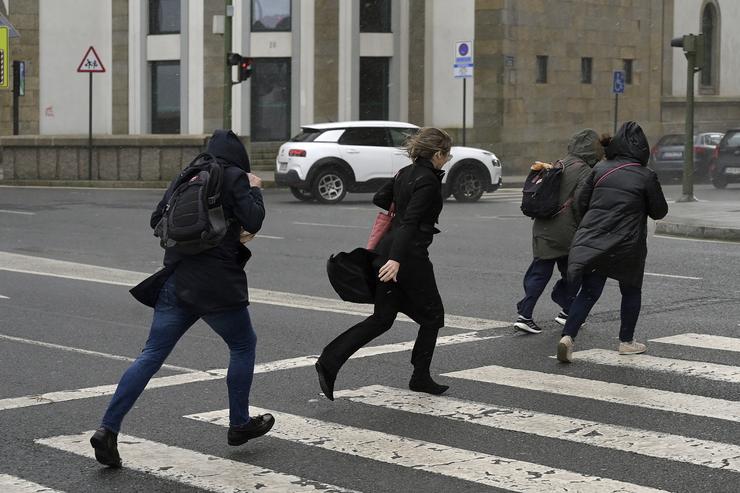 Varias persoas corren baixo a choiva durante a fronte meteorolóxica, a 23 de febreiro de 2024, na Coruña 